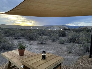 A wooden table with a potted plant and a water bottle under a canopy in a desert landscape. - Serene Glamping Tent Incredible to Relax and Disconnect in Delta, Colorado (Delta)