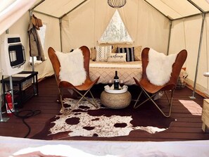 A tent with two leather chairs, a small table with a bottle and glasses, and a cowhide rug. - Serene Glamping Tent Incredible to Relax and Disconnect in Delta, Colorado (Delta)