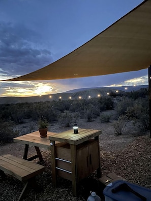 An outdoor camping setup with a table, a lantern, and a portable cabinet under a shade sail. - Serene Glamping Tent Incredible to Relax and Disconnect in Delta, Colorado (Delta)