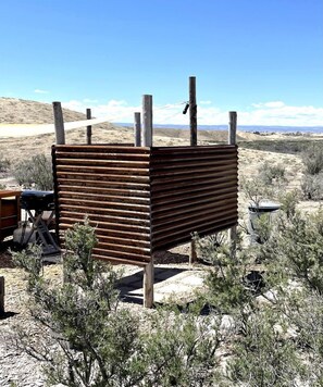 A rustic wooden structure with a metal roof, surrounded by sparse vegetation and a clear sky. - Serene Glamping Tent Incredible to Relax and Disconnect in Delta, Colorado (Delta)