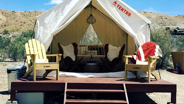 A tent with 'TENTR' branding, two wooden Adirondack chairs, a table, and a hanging light fixture. - Serene Glamping Tent Incredible to Relax and Disconnect in Delta, Colorado (Delta)