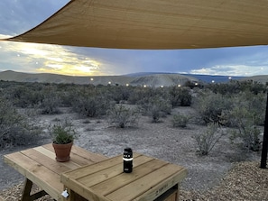 A wooden table with a potted plant and a water bottle under a canopy in a desert landscape. - Serene Glamping Tent Incredible to Relax and Disconnect in Delta, Colorado (Delta)
