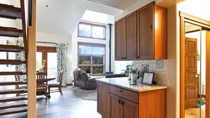 Une cuisine avec des meubles de rangement en bois, un plan de travail et un coin repas comprenant une table et des chaises.
