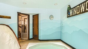 Ein Zimmer mit einer großen Badewanne, einer Holztür und einer Wand mit Bergmotiv.