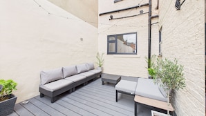 Un patio con un sofá gris, una mesita y plantas en macetas.