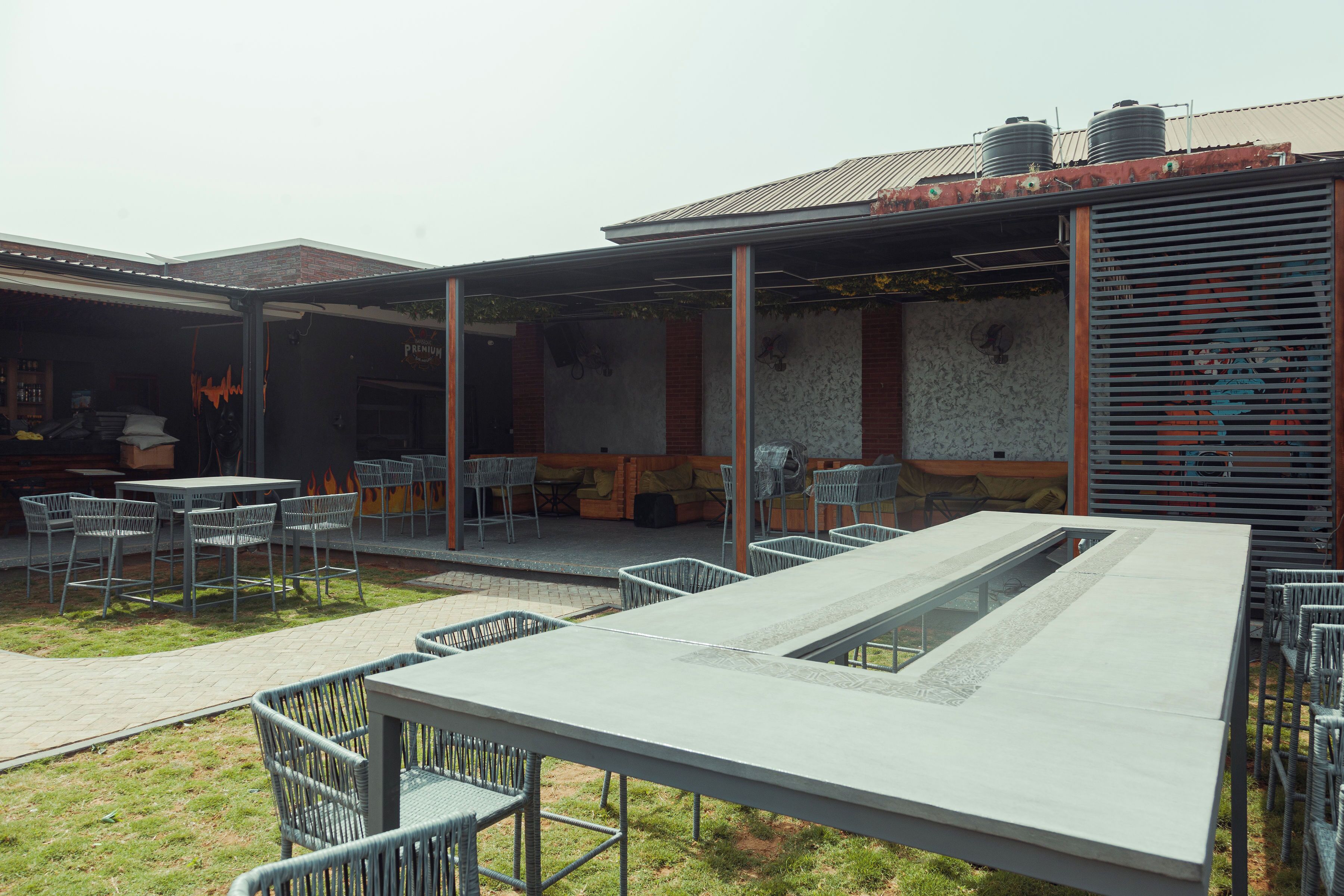 An outdoor seating area with tables and chairs, a long bench, and a water feature.