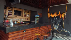 A bar area with wooden bar counter, stools, and shelves stocked with bottles and glasses. - Grayville Hotels and Bistro (Akure)