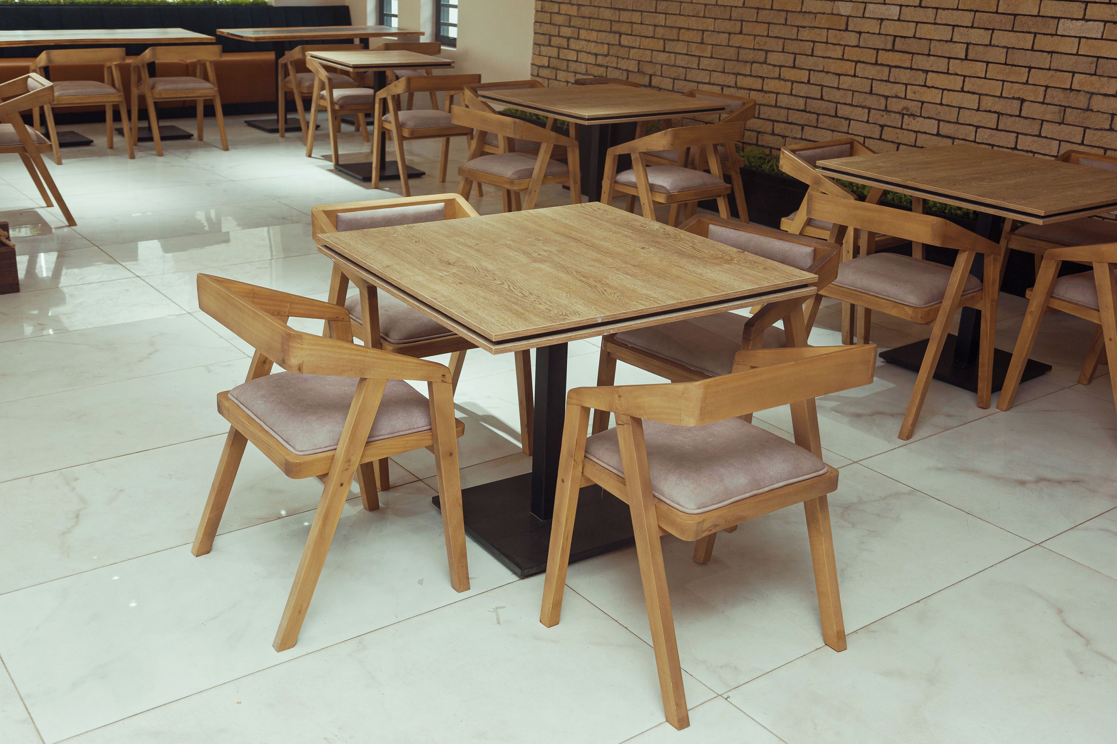 A restaurant with wooden tables and chairs, a tiled floor, and a brick wall.