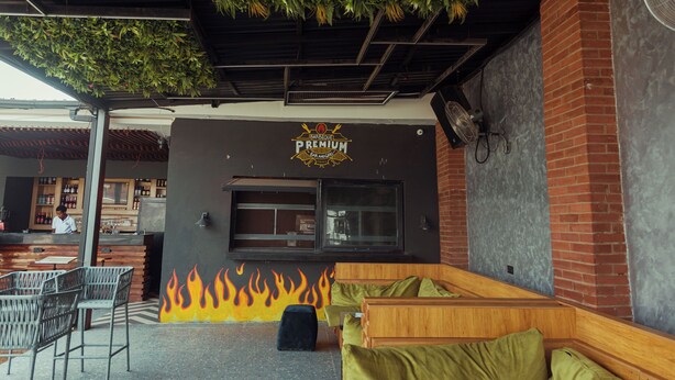 An outdoor seating area with a fire mural, a bar, and a grill station. - Grayville Hotels and Bistro (Akure)
