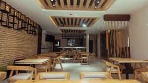 A restaurant with wooden tables and chairs, a brick wall, and a modern ceiling design. - Grayville Hotels and Bistro (Akure)