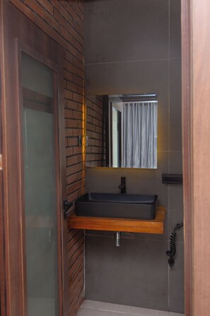 Un baño con tocador de madera, un espejo y una ducha.