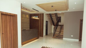 A modern interior with a wooden reception desk, a staircase, and a bench. - Grayville Hotels and Bistro (Akure)