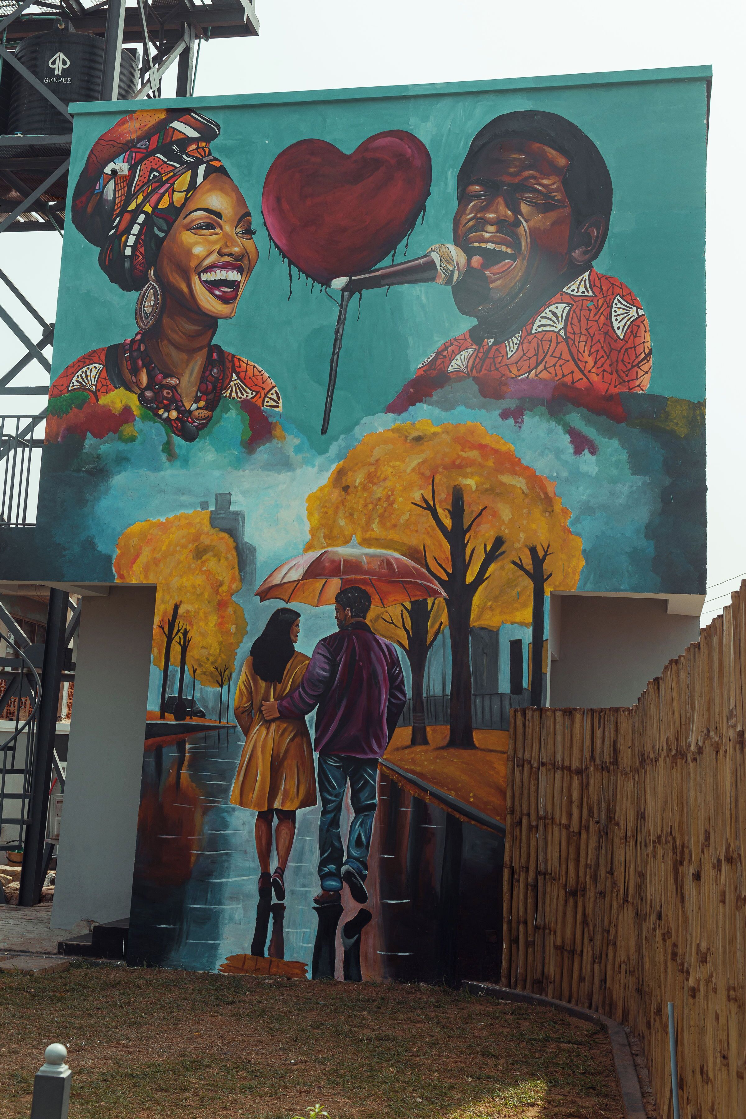 Un mural con una pareja bajo un árbol, un corazón y un micrófono.