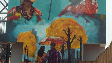Un mural con una pareja bajo un árbol, un corazón y un micrófono.