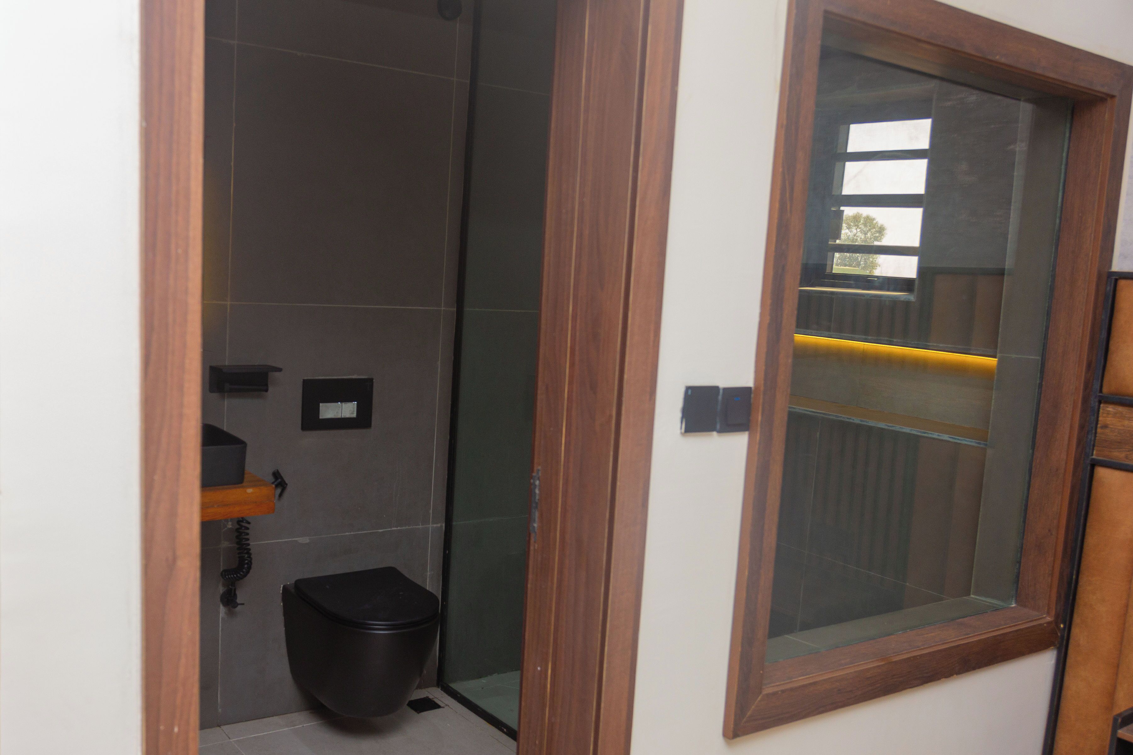 A bathroom with a shower, toilet, and a window with a wooden frame.