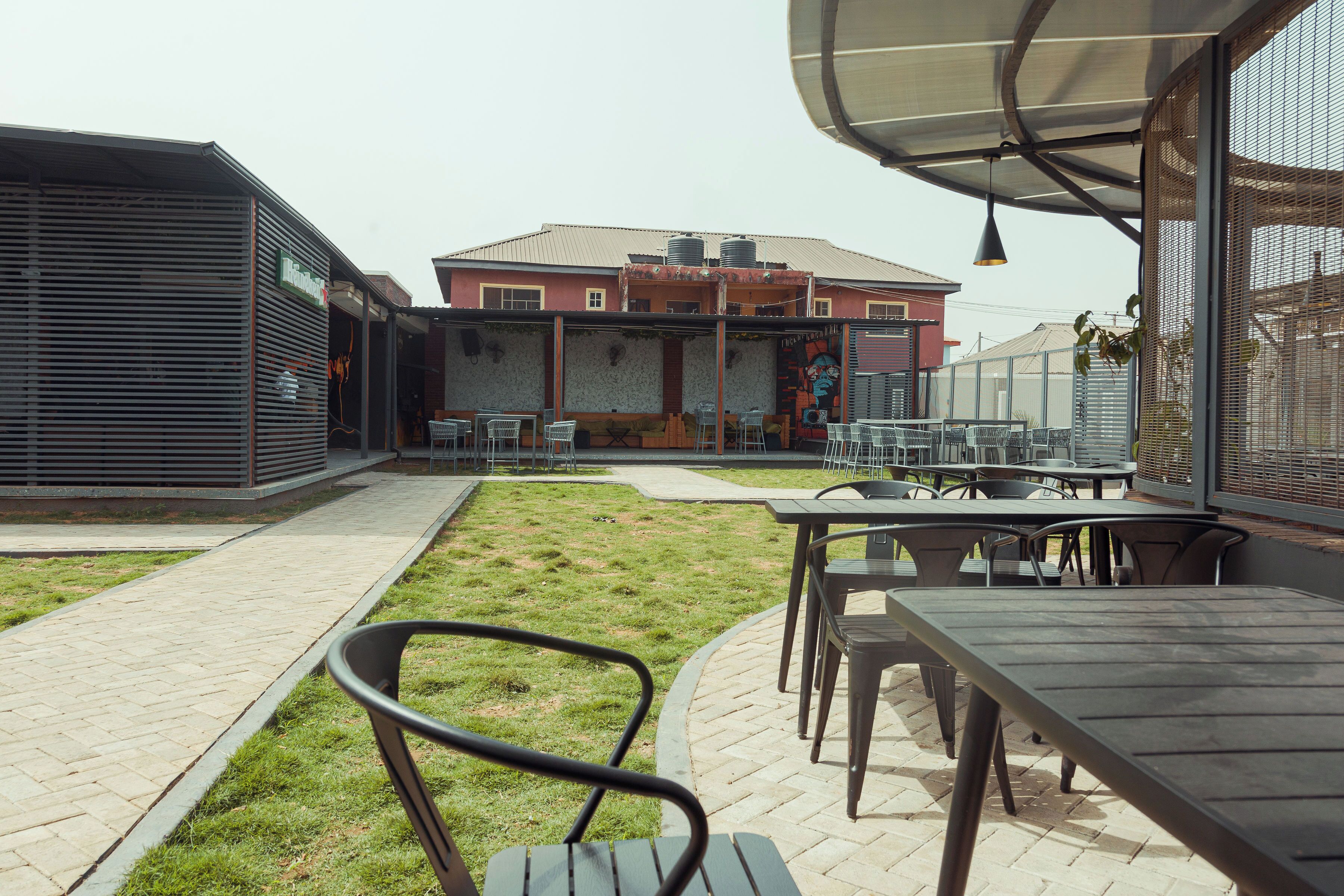 A patio area with outdoor seating, a pathway, and a building with a red facade and a mural.