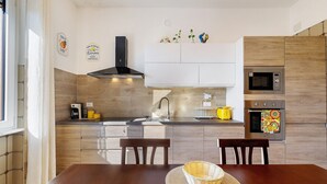 Eine moderne Küche mit Holztisch, Stühlen, einer Mikrowelle, einem Backofen und einem Spülbecken.