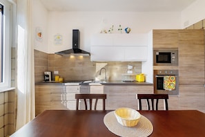 Une cuisine moderne avec une table en bois, des chaises, un four à micro-ondes, un four traditionnel et un évier.