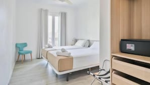 Een hotelkamer met een bed, een stoel, een bureau en een plafondventilator.