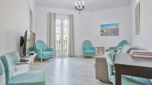 Een moderne woonkamer met blauwgroene fauteuils, een houten salontafel en een kroonluchter.