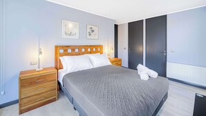 A bedroom with a bed, wooden nightstands, a dresser, a radiator, and two framed pictures on the wall. - Urban Bloom 3D, Wifi y Estacionamiento (Ñuñoa)