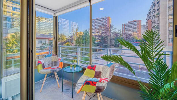 A balcony with two chairs, a small table, and a potted plant. - Urban Bloom 3D, Wifi y Estacionamiento (Ñuñoa)