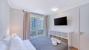 A hotel room with a bed, a TV, a balcony with chairs, and a white wardrobe. - Vista Infinita (Concón)
