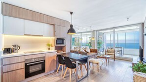 Uma cozinha moderna com área de refeições, grandes janelas e vista para o oceano.