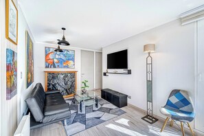 A modern living room with a sofa, coffee table, and a unique blue chair. - City Retreat - 2D - Wifi & Parking in Barrio Italia (Ñuñoa)