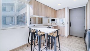 Una cocina moderna con comedor, armarios de madera y un amplio ventanal.