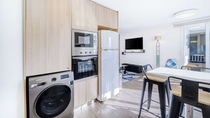 Una cocina compacta equipada con lavadora, microondas, horno y refrigerador.