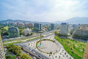 A cityscape with modern buildings, a central roundabout, and a prominent vertical structure.