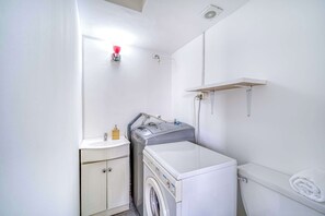 Een kleine wasruimte met een wasmachine, een droger, een wastafel en een handdoekrek.