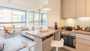 Une cuisine moderne dotée d’un îlot central, d’un four encastré et de grandes fenêtres offrant une vue sur la ville.