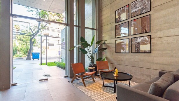 Un hall d’entrée moderne avec une grande porte en verre, deux fauteuils en cuir, un canapé et une table basse.