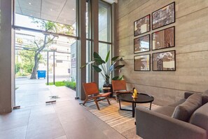 Un vestíbulo moderno con un gran puerta de vidrio, dos sillones de cuero, un sofá y una mesita de centro.