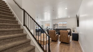 A spacious living area with a staircase, a leather sofa, and a dining table. - Sand Hollow Serenity: Private Hot Tub (Washington)