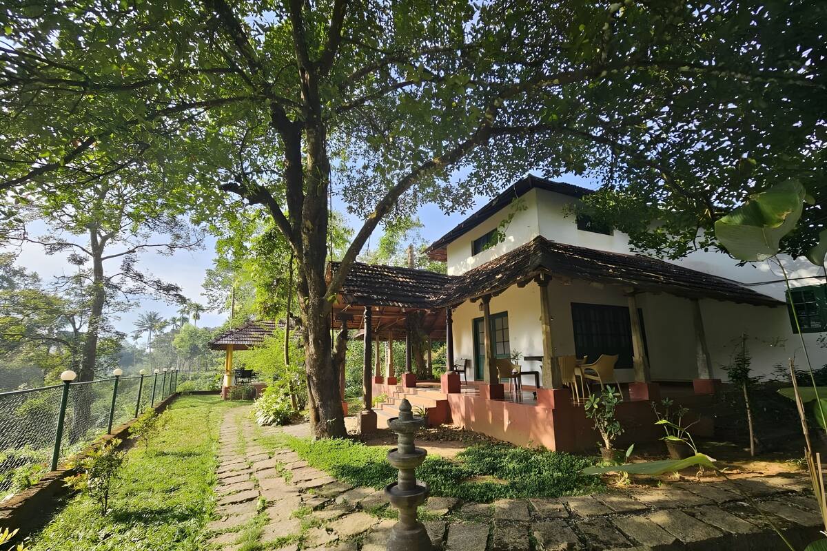 A traditional house with a tiled roof, a porch with chairs, and a stone pathway leading to the entrance.
