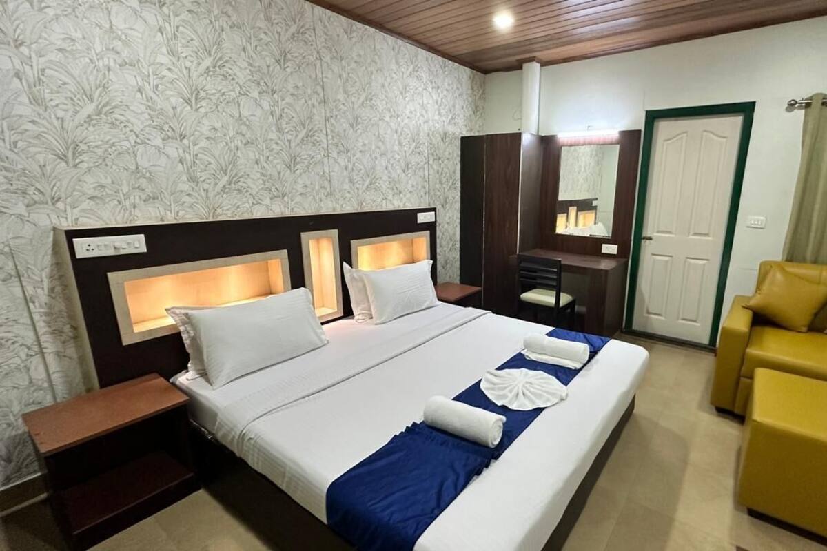 A hotel room with a large bed, a desk, a chair, and a sofa.