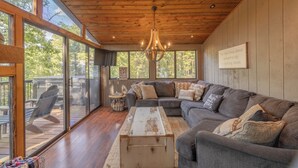 A spacious living room with a large sectional sofa, a wooden coffee table, and a chandelier.
