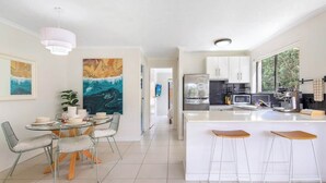Una cucina moderna con mobili bianchi, un frigorifero in acciaio inossidabile e una grande isola con sgabelli da bar.