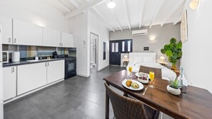 Een moderne keuken met witte kasten, een fornuis en een ontbijtgedeekte eettafel.