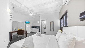 Een hotelkamer met een groot bed, een bureau, een stoel, een televisie en een kitchenette.