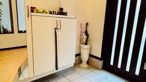 A white cabinet with a 'WELCOME' sign, a white trash bin, and a black door with vertical stripes. - Nagomi no Yado Umeda 1 station 3 min. walk from station 1 building 4 rooms for private use Kyoto-Kobe direct access (大阪市淀川区十三本町2丁目)