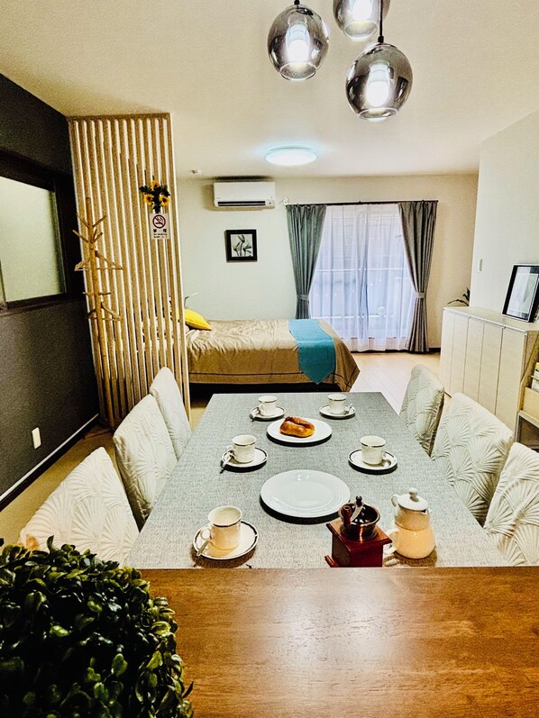 A modern hotel room with a dining area, a bed, and a kitchenette.