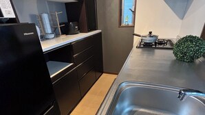 A modern kitchen with a stainless steel sink, black cabinetry, and a small window with a view of the sky. - Nagomi no Yado Umeda 1 station 3 min. walk from station 1 building 4 rooms for private use Kyoto-Kobe direct access (大阪市淀川区十三本町2丁目)