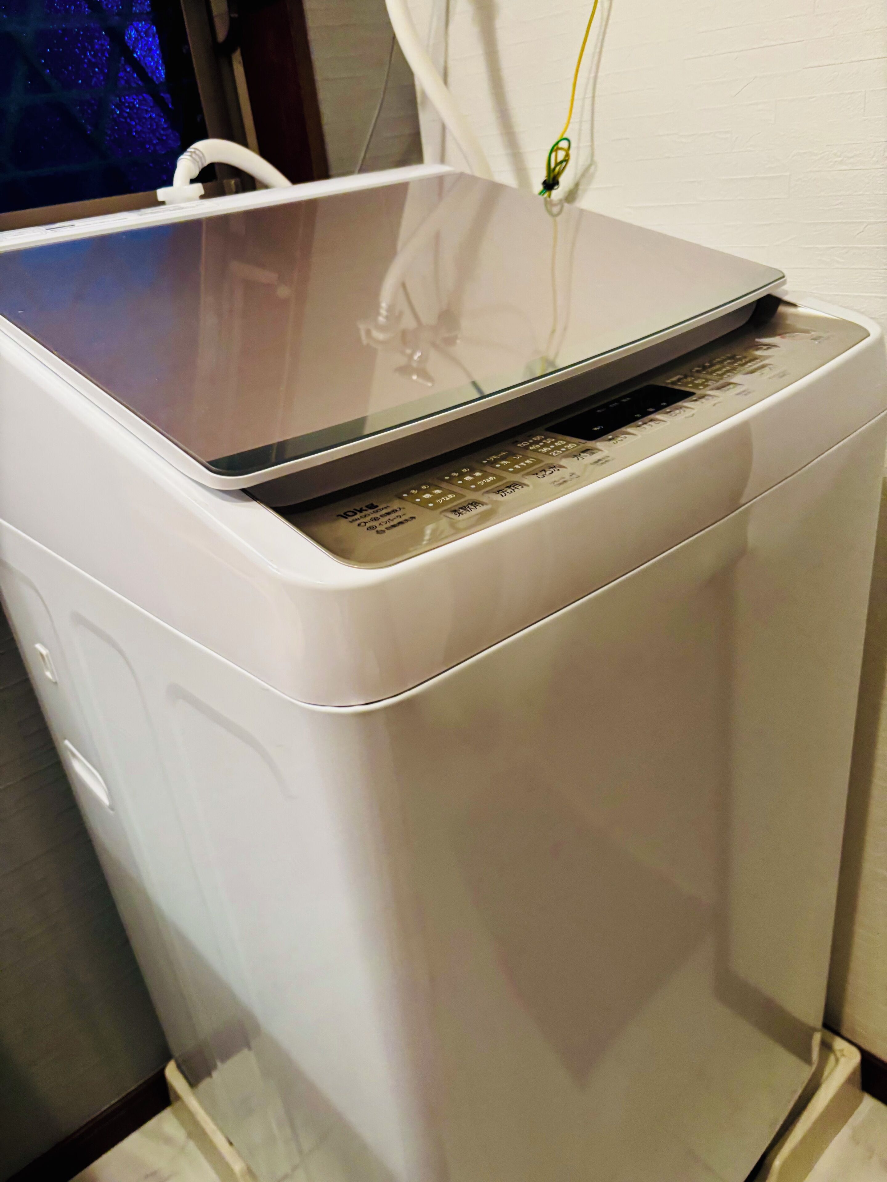 Un elettrodomestico bianco con coperchio trasparente, forse una macchina per caffè o un piccolo apparecchio da cucina, dotato di pannello di controllo e cavo di alimentazione inserito.