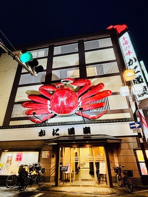 A building with a large crab decoration above the entrance, a sign with Japanese characters, and bicycles parked outside.