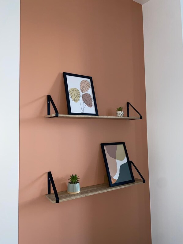 Two wall-mounted shelves with artwork and small potted plants.