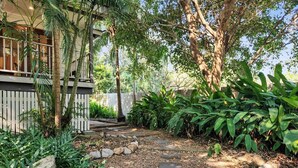 Un sendero de jardín con losas, rodeado de exuberante follaje y árboles.